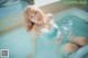 A woman in a blue bikini sitting in a bathtub.