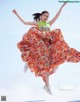 A woman in a colorful dress jumping in the air.