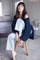 A woman sitting on a wooden chair in a room.