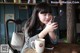 A woman sitting at a table with a cup of coffee and a cell phone.