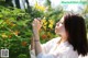 A woman smelling a yellow flower in a park.