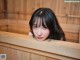 A woman with long black hair sitting in a wooden bathtub.