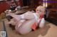 A woman in a white and orange outfit is laying on the floor.