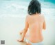 A woman in a white bikini sitting on the beach.