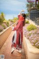 A woman in a red dress is dancing on a brick walkway.