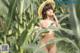 A naked woman in a straw hat standing in a corn field.