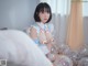 A woman sitting on top of a bed surrounded by balloons.