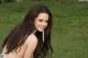 A woman with long brown hair posing in the grass.