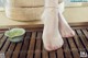 A woman's feet with a bowl of green tea on a bamboo mat.