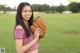 A young woman holding a baseball glove on a field.