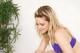 A woman in a purple bikini sitting next to a plant.