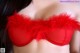 A woman wearing a red bra with red feathers on it.